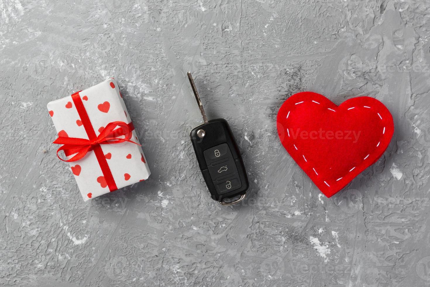 Valentine or other holiday handmade present in paper with red hearts, car keys and gifts box in holiday wrapper. box gift on gray cement table top view with copy space, empty space for design photo