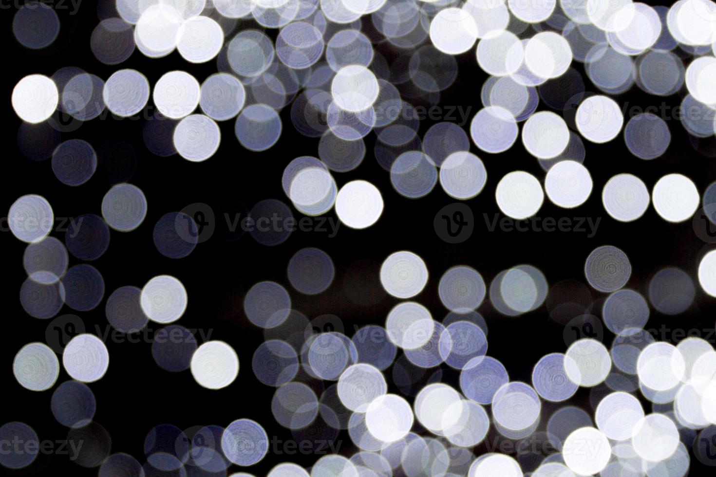Bokeh white lights on black background. Abstract defocused many round light photo
