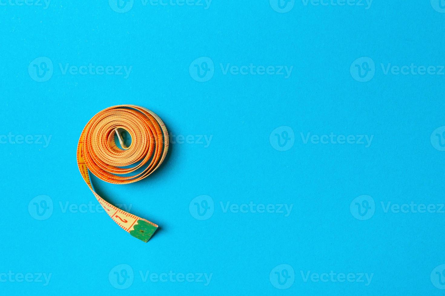 Rolled tape measure with space for your design. Top view of slim waist concept on blue background photo