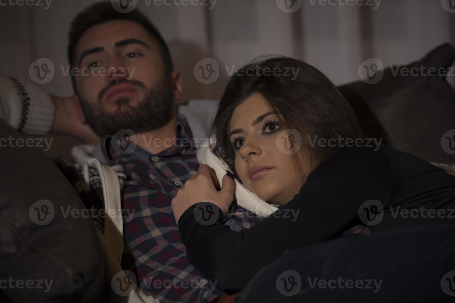 pareja joven viendo la televisión por la noche en casa foto