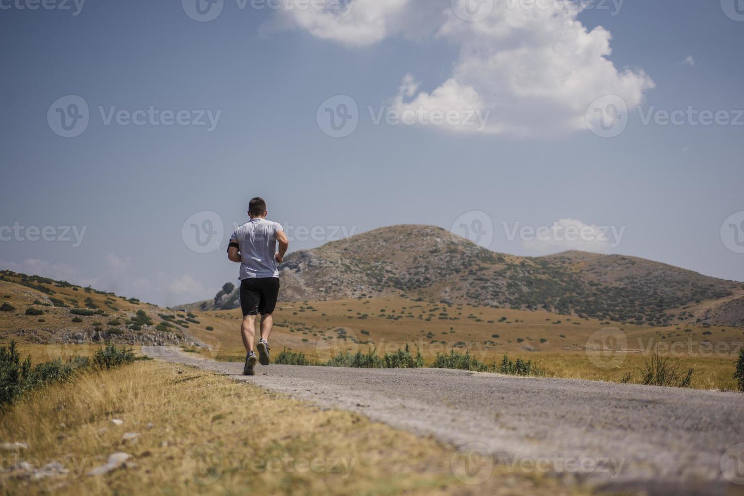 corredor de hombre deportivo corriendo en la meseta de la montaña en verano foto