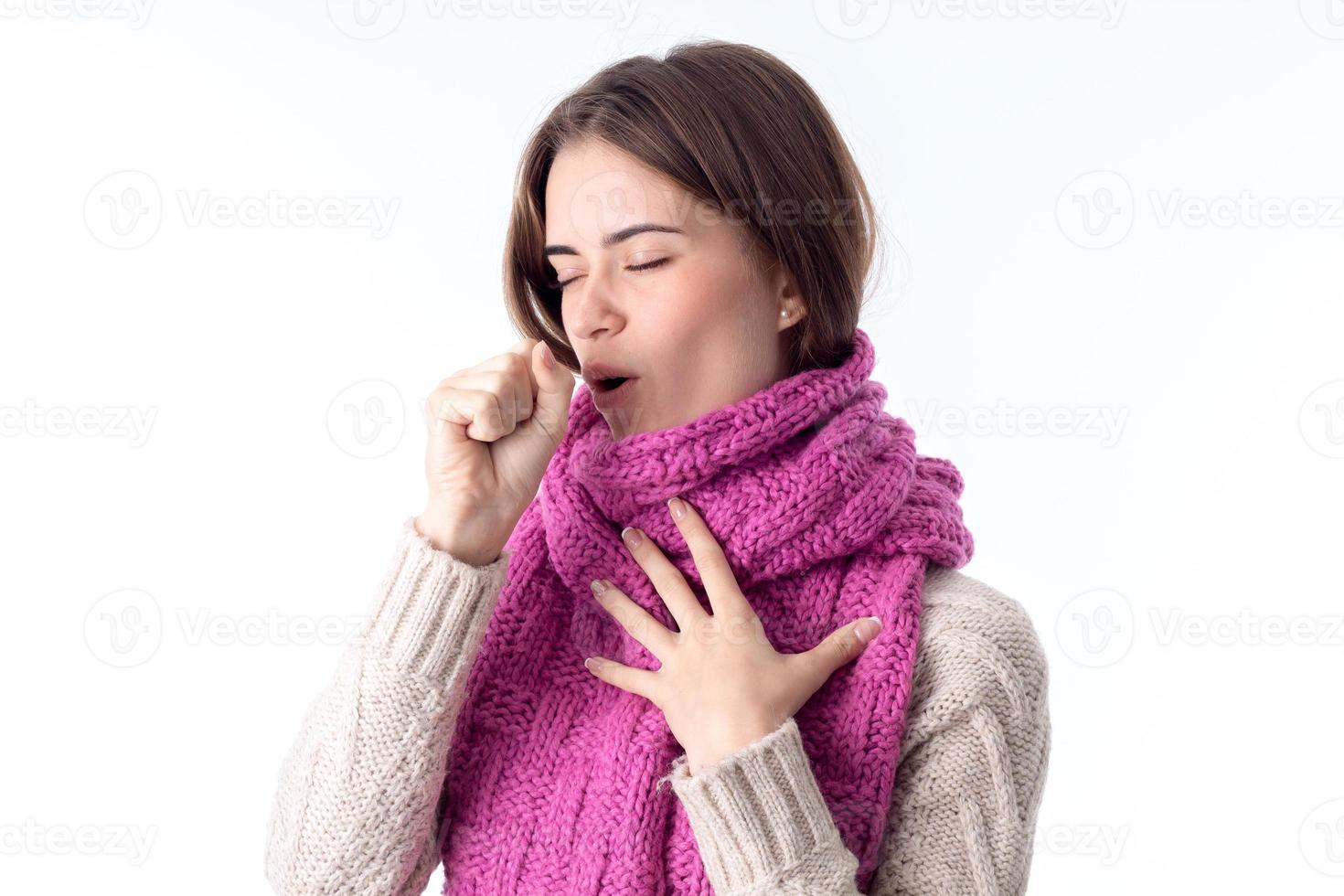 girl in a warm scarf coughs isolated on white background photo