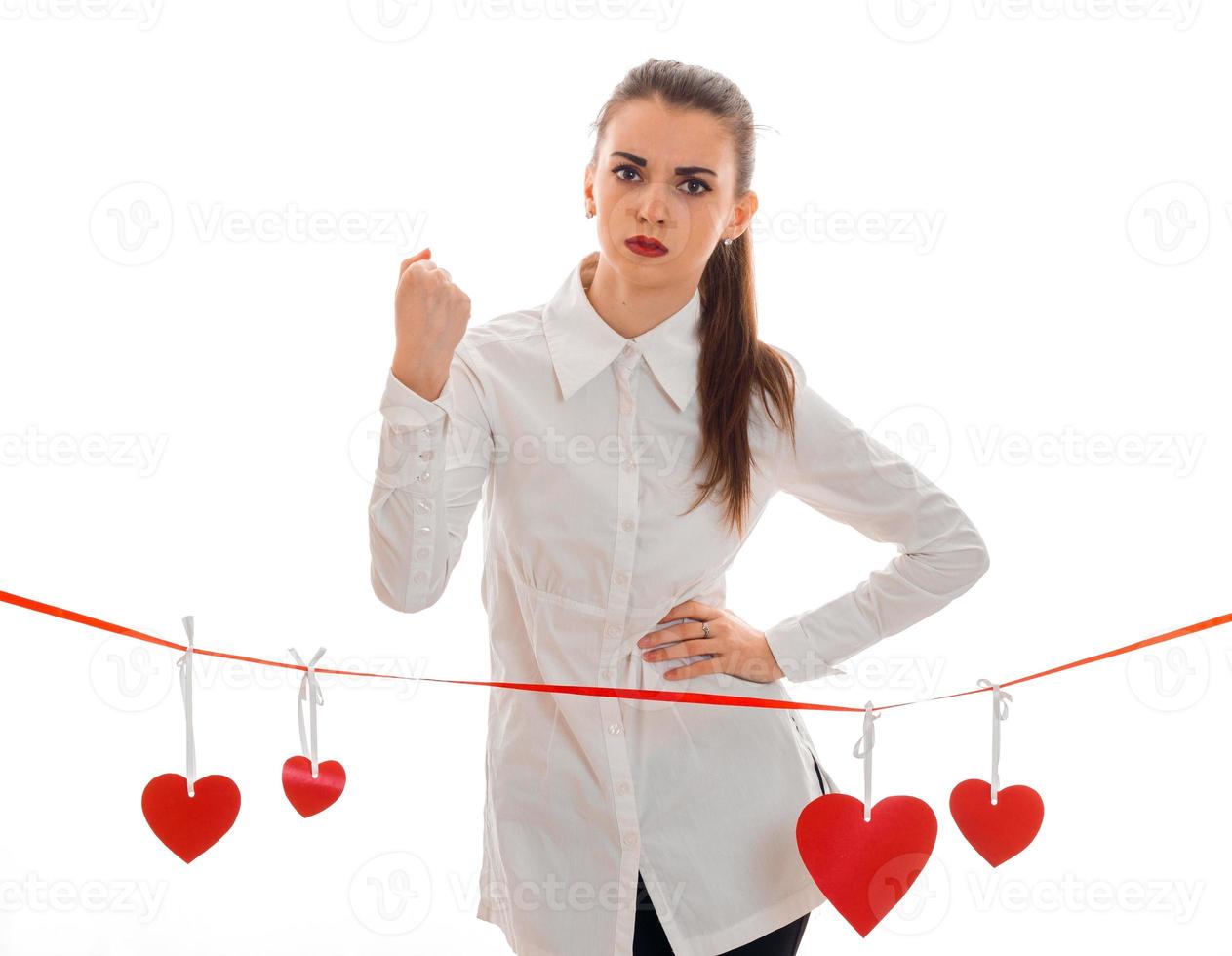 hermosa joven con camisa blanca y pintalabios rojo en los labios se encuentra cerca de la cinta con tarjetas en forma de corazón foto