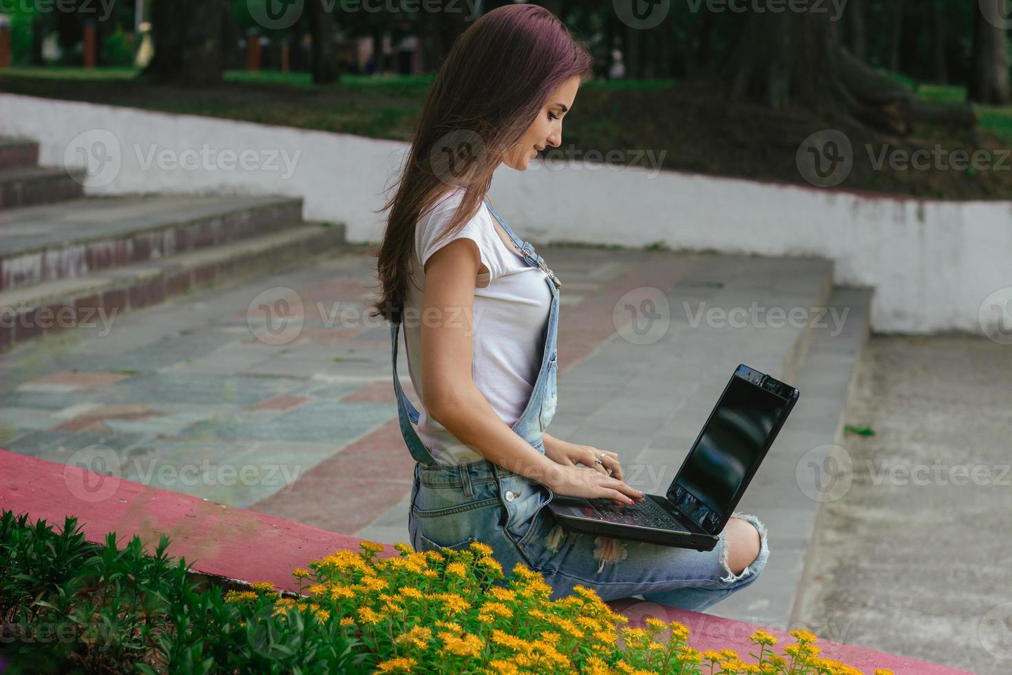a slender young woman sitting with a laptop photo
