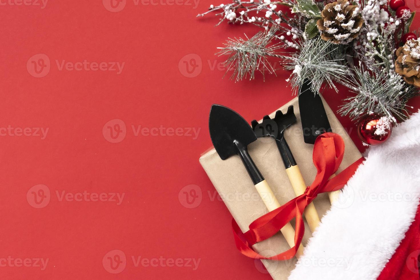 Christmas and new year composition with garden tools, shovel and rake and Santa Claus hat on a red background. The concept of gardening and farming for cards, calendars, covers. photo