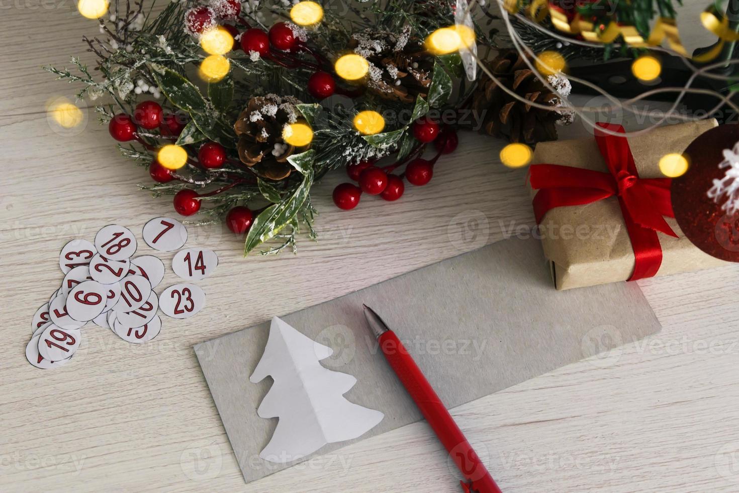 Advent calendar on wooden background with christmas tree branch and blur light. photo