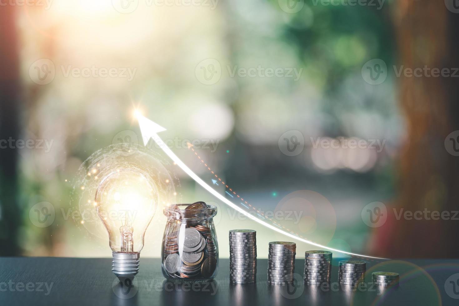 light bulb, a glass jar, and some coins lay on table,finance and banking, fund growth and savings concept, proportional money management to spend effectively,interest growth graph, plan for retirement photo