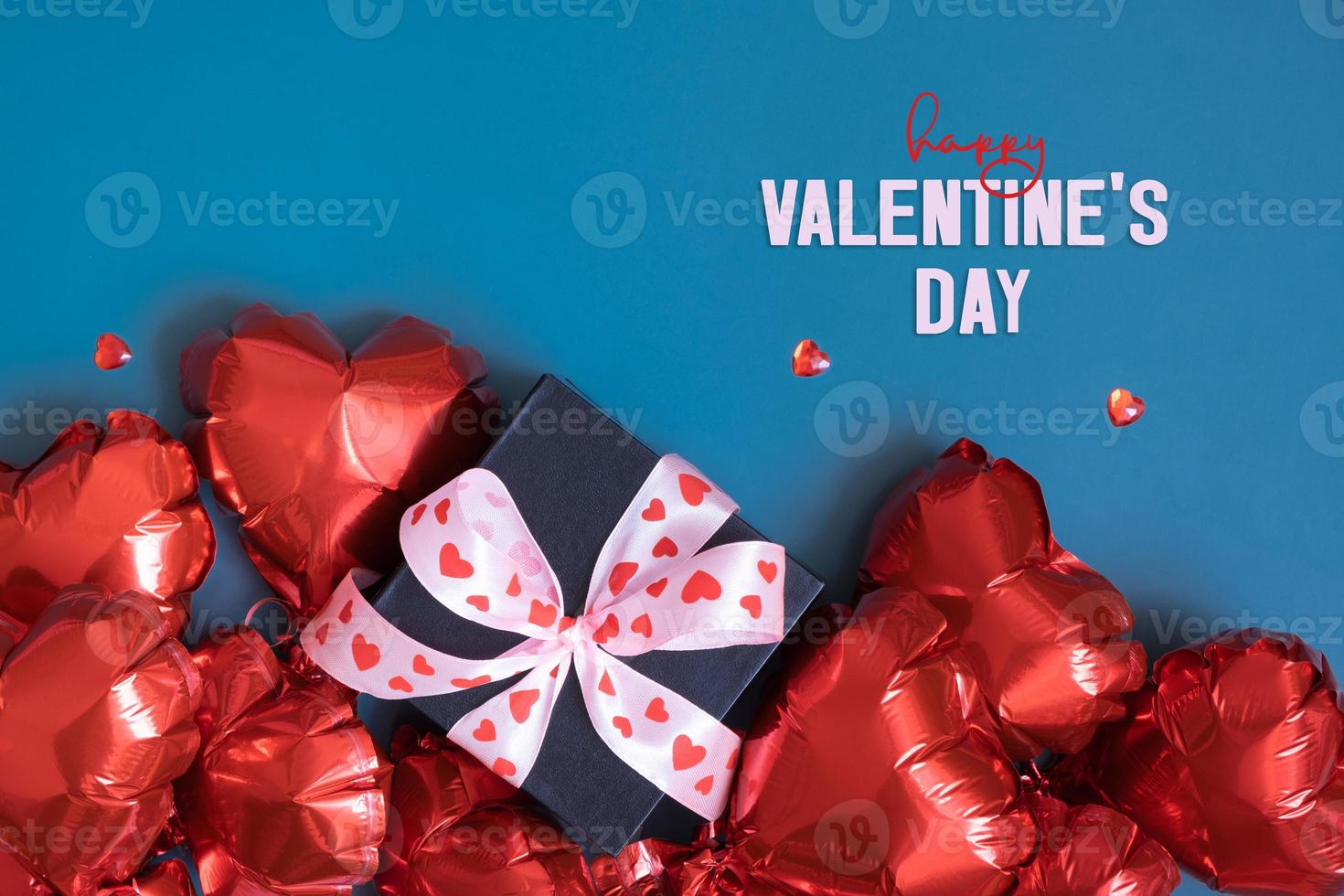 Happy Valentines Day text and gift box with red heart shape baloons on blue background. Valentines Day greeting card photo