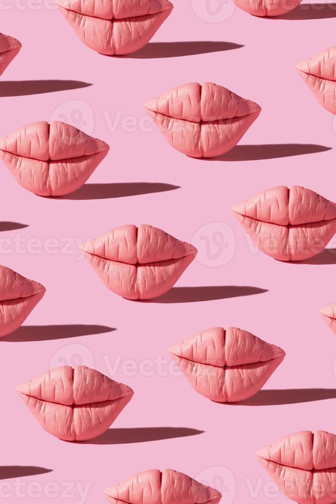 Pattern from pink lips on pink background. Creative beauty concept vertical background photo