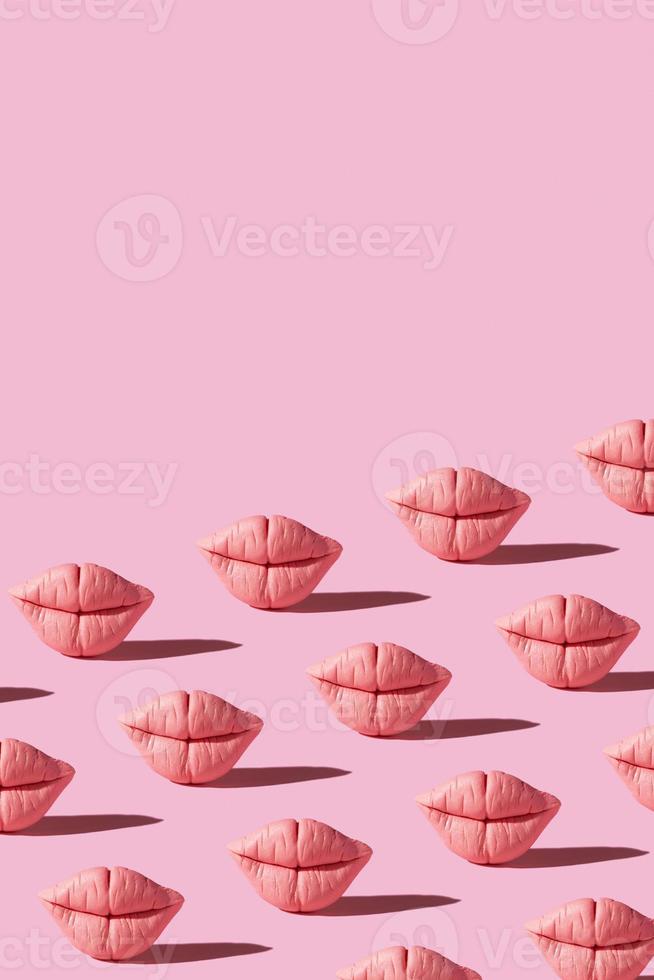 Pattern from pink lips on pink background. Creative beauty concept vertical background photo