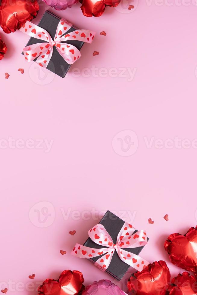 Present gift box with bow and heart shape baloons on pink background. Valentines Day background with copy space photo