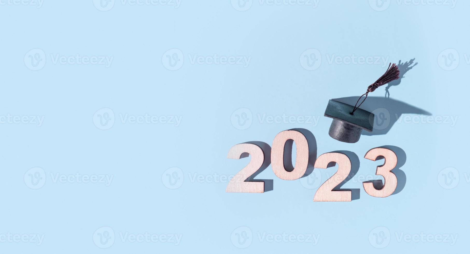 Class of 2023 concept. Numbers 2023 with black graduated cap on colored background photo