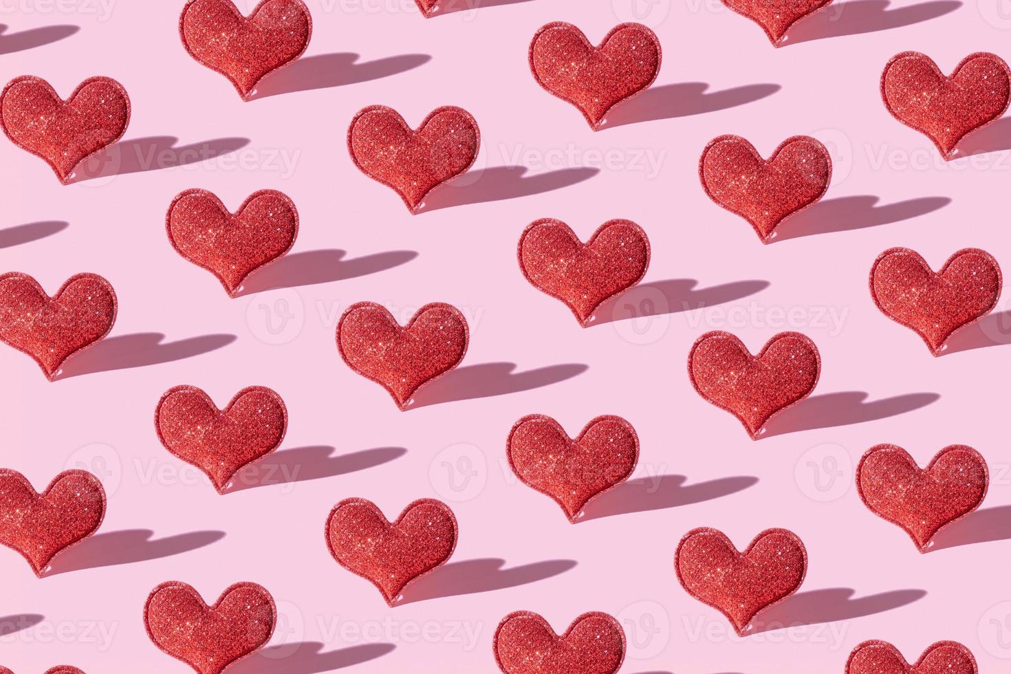 Pattern with red glitter heart shape on pink background with hard shadow.  Valentines day minimalistic symbol love photo