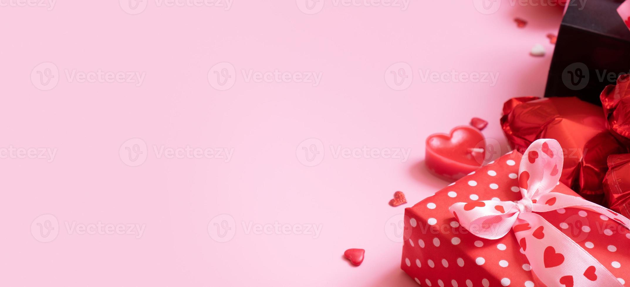 caja de regalo, velas y globos con forma de corazón rojo sobre fondo rosa. pancarta del día de san valentín foto