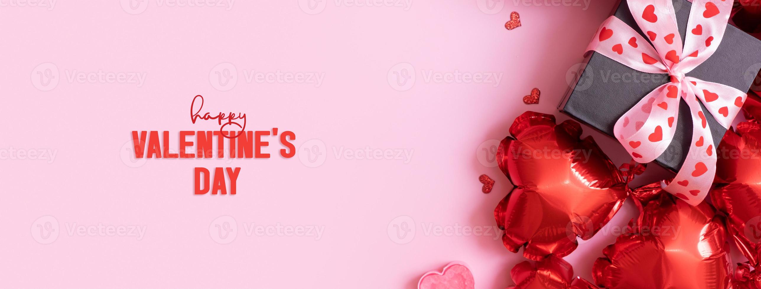 Happy Valentines Day text on greeting card. Banner with gift box with bow and heart shape baloons on pink background photo