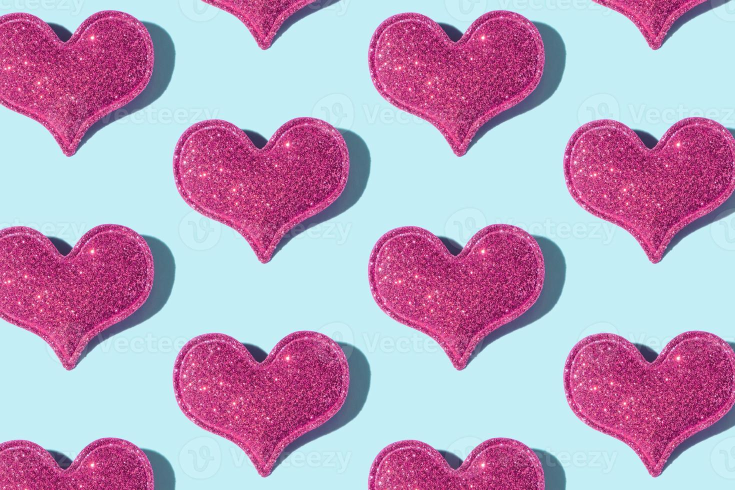 Pattern made from glitter heart shape on colored background with hard shadow. Valentines day minimalistic design photo