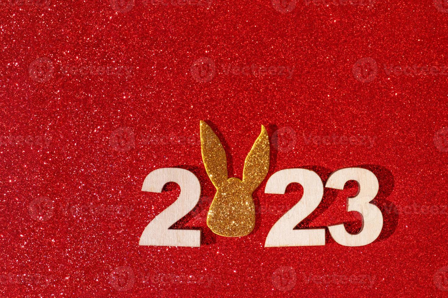 Wooden numbers 2023 with rabbit ears symbol new year on a colored background photo