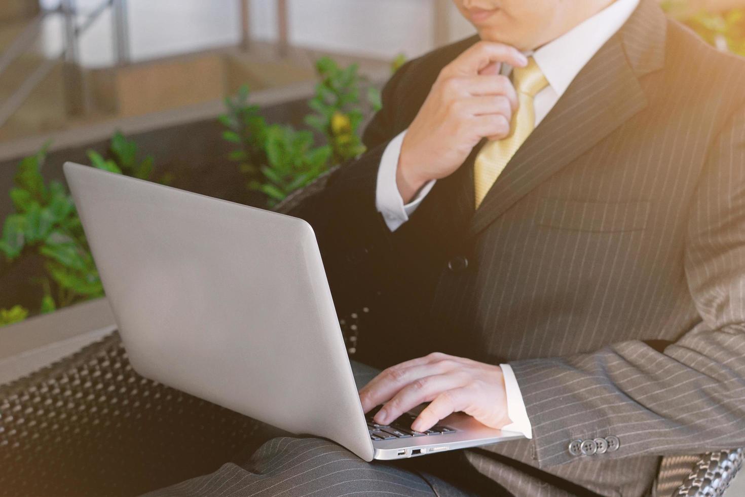 Selective focus of Businessman work on Laptop keyboard and thinking. Man concentrate working computer notebook with hand touching chin. business solution, target goal, serious problem concept photo