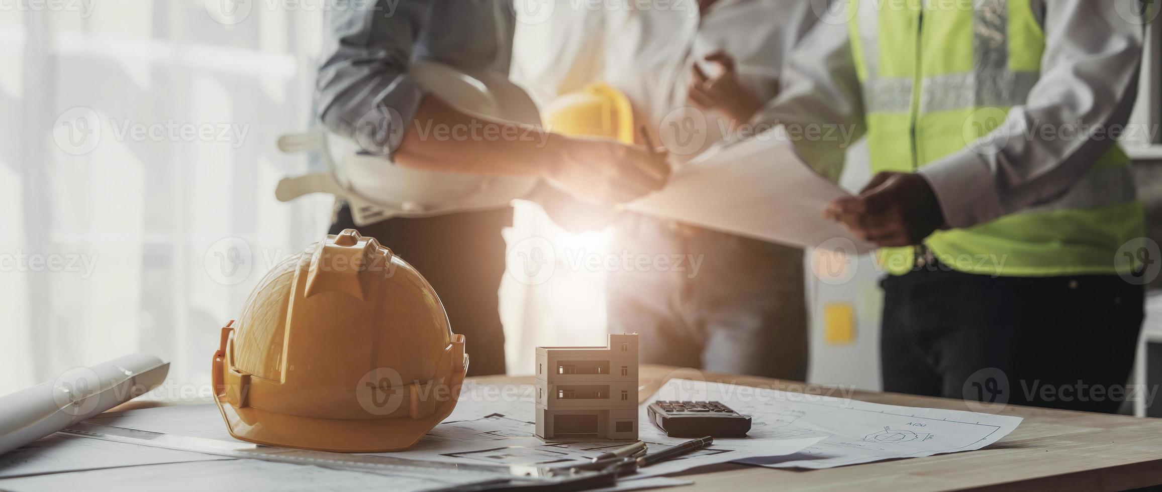 Civil engineer teams meeting working together wear worker helmets hardhat on construction site in modern city. Foreman industry project manager engineer teamwork. Asian industry professional team photo