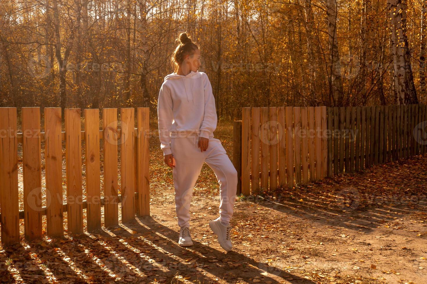 girl stands near a wooden fence in the fall photo