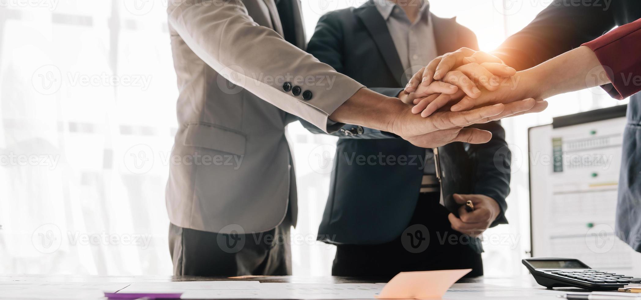Group of business people putting their hands working together on wooden background in office. group support teamwork agreement concept. photo