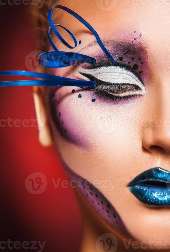 half face of beauty woman with creative make up in studio on red photo