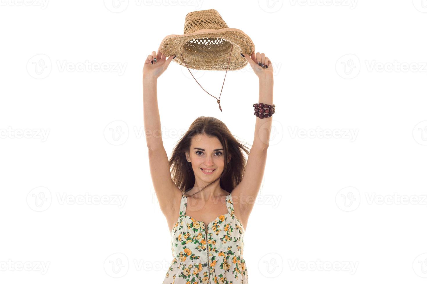 cheerful young girl in sarafan with floral patter and straw hat with wide brim smiling and looking at the camera isolated on white background photo