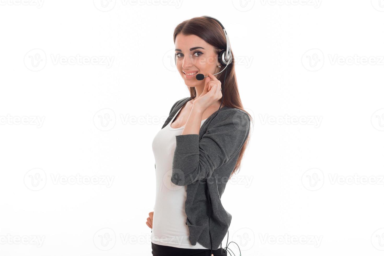 young girl in grey jacket stands sideways and keeps hand microphone with headphones, photo