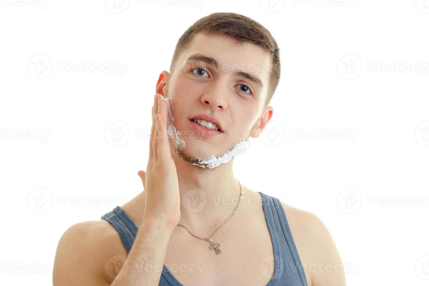 Portrait of a handsome young guy who looks straight into the camera and shaving foam on your face photo