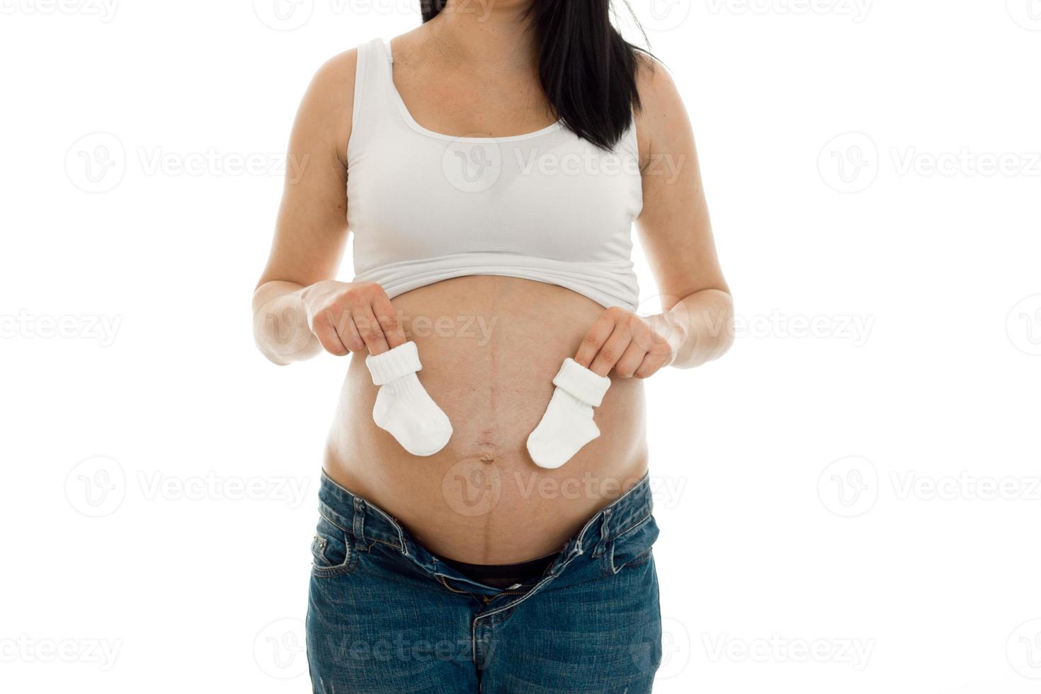 beautiful young pregnant woman holding socks have a tummy tuck photo