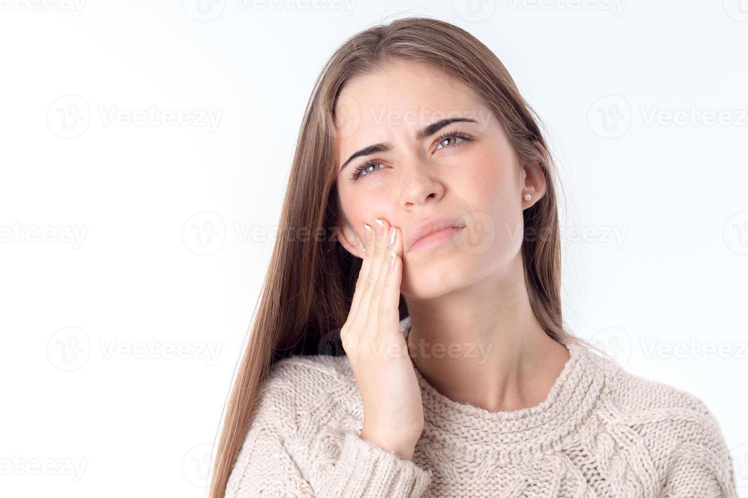 girl feels toothache looks up and keeps your hand for face isolated on white background photo