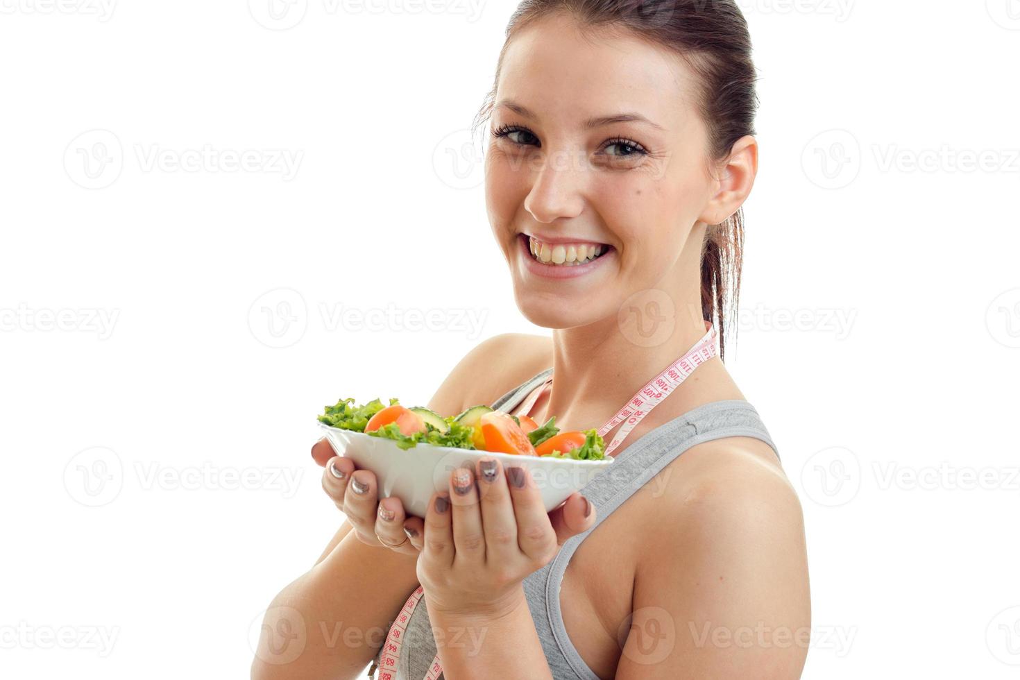 Portrait of a remarkable young girl who laughs and holds a large plate of vegetable salad closeup photo