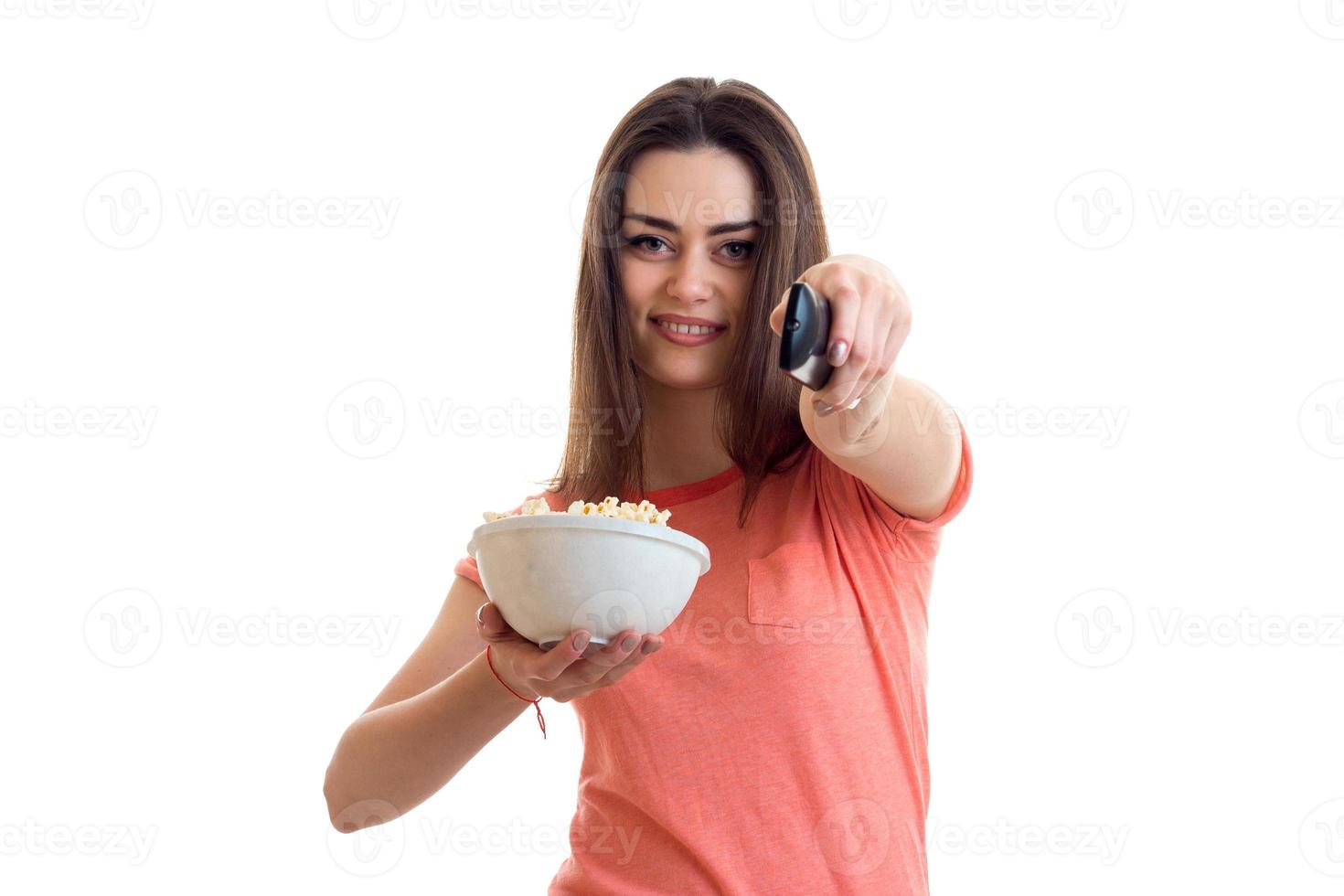 cute young girl with pop-corn stretched forth her hand and changes channels remote control photo