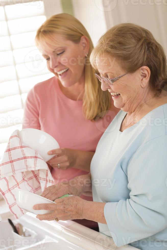 Senior Adult Woman and Young Daughter Talking in Kitchen photo