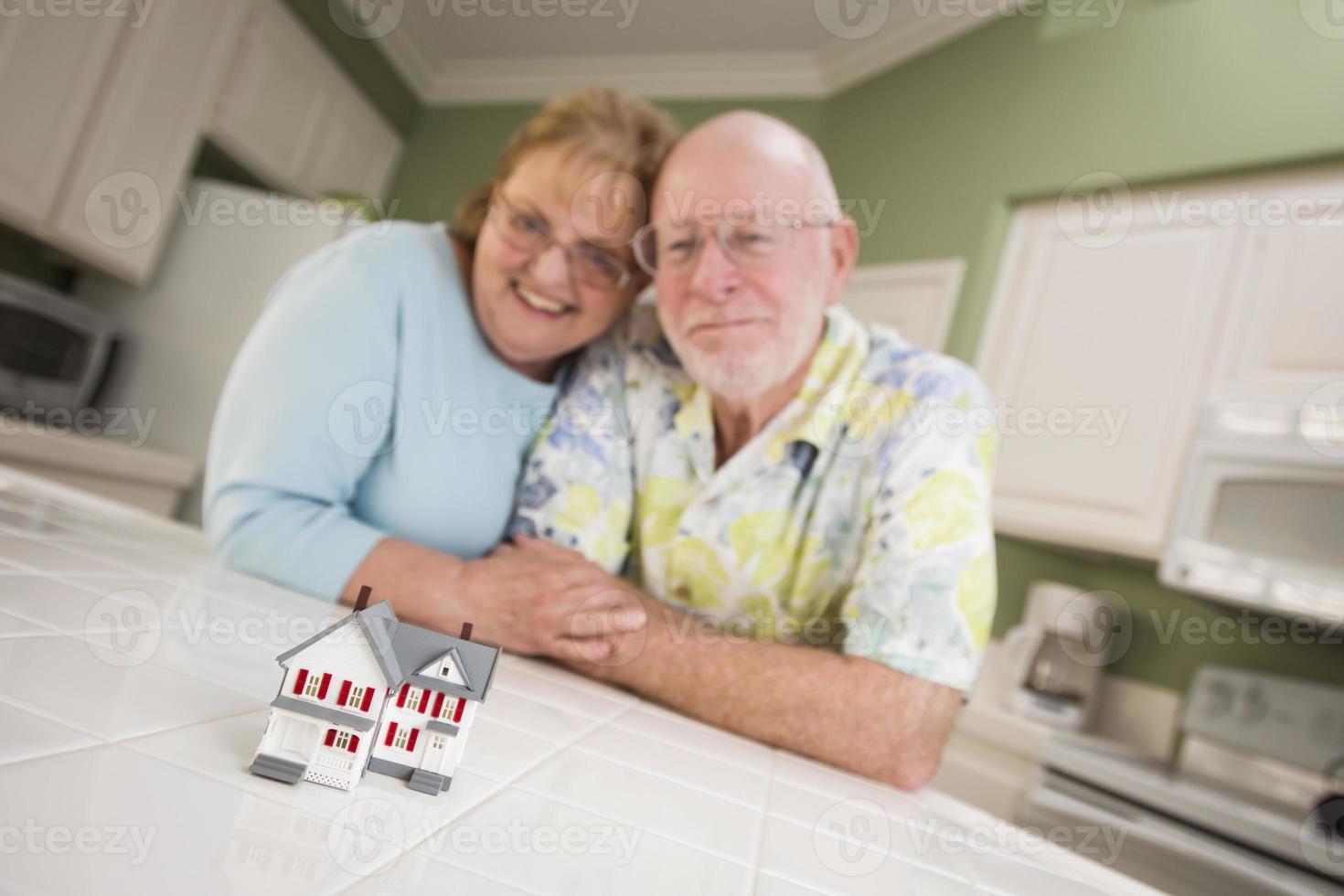 Senior Adult Couple Gazing Over Small Model Home on Counter photo