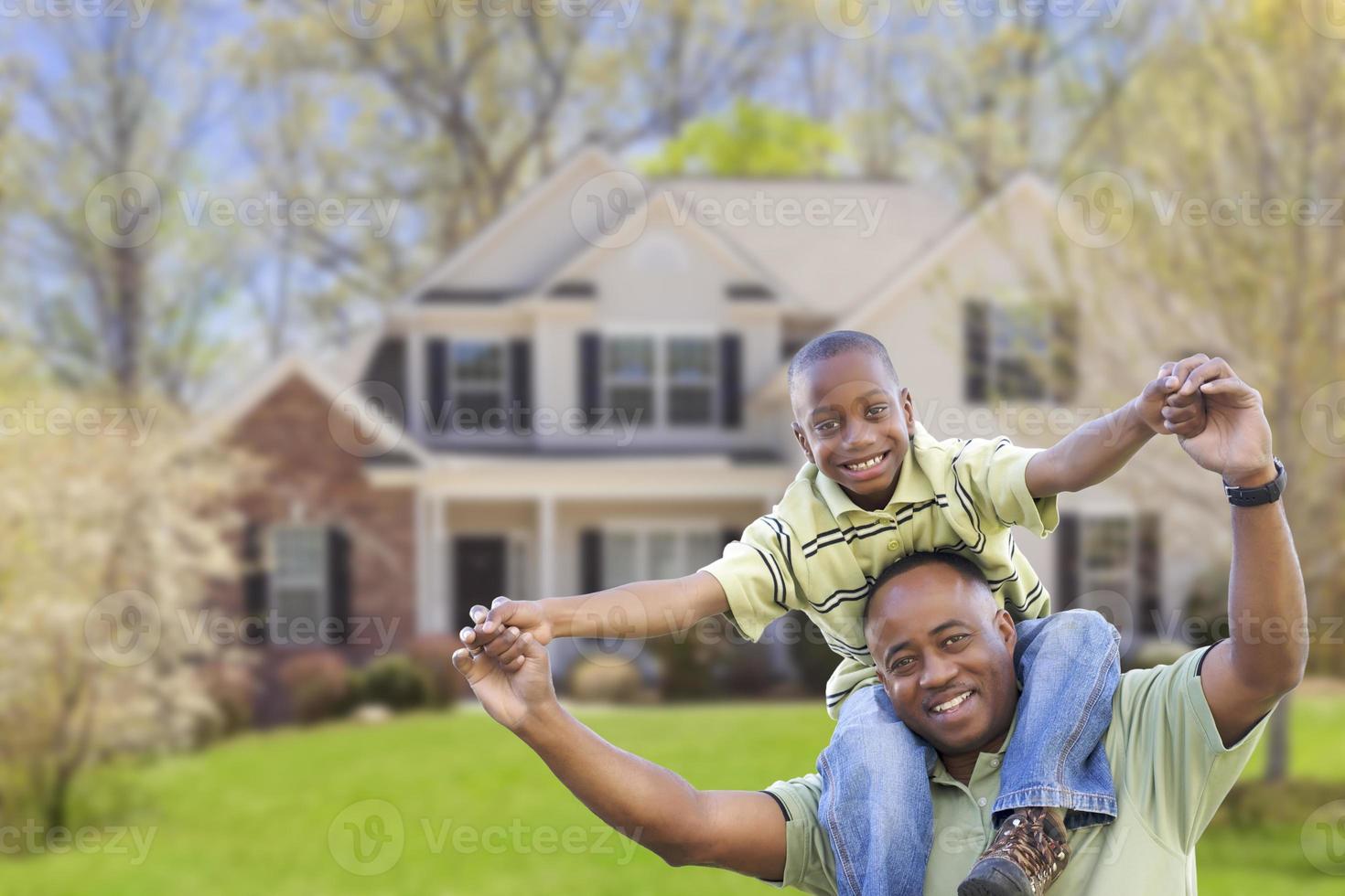 padre afroamericano juguetón e hijo frente a casa foto