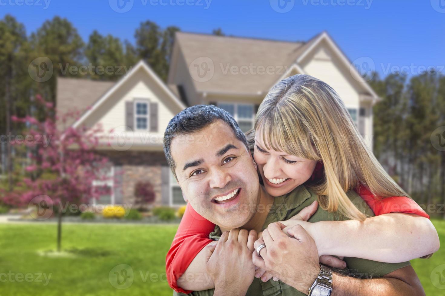 pareja de raza mixta abrazándose frente a la casa foto