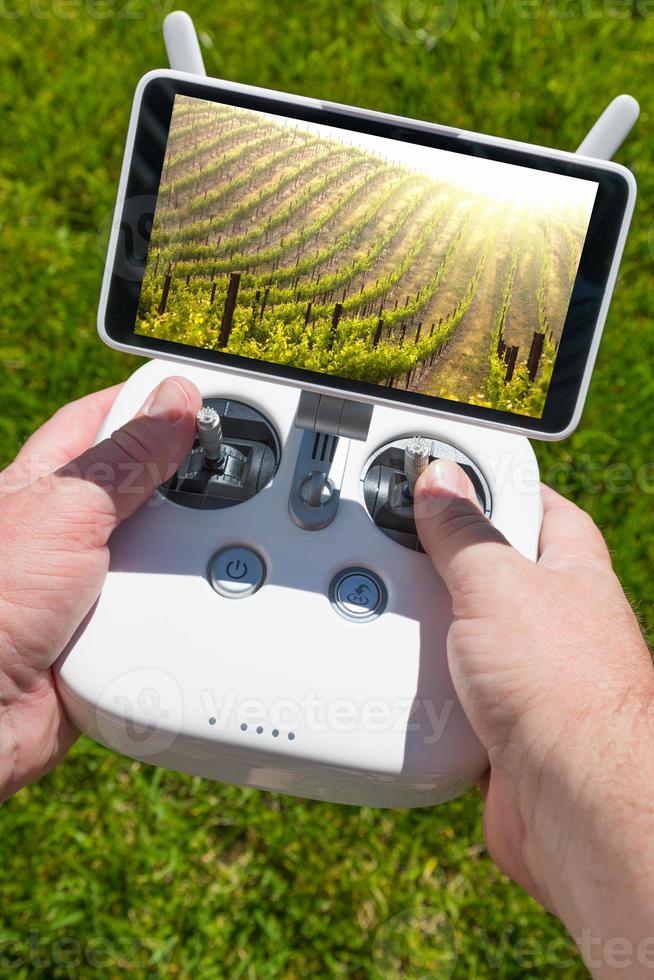 manos sosteniendo un controlador de cuadricóptero de drones con una hermosa vista del viñedo de uva en la pantalla foto