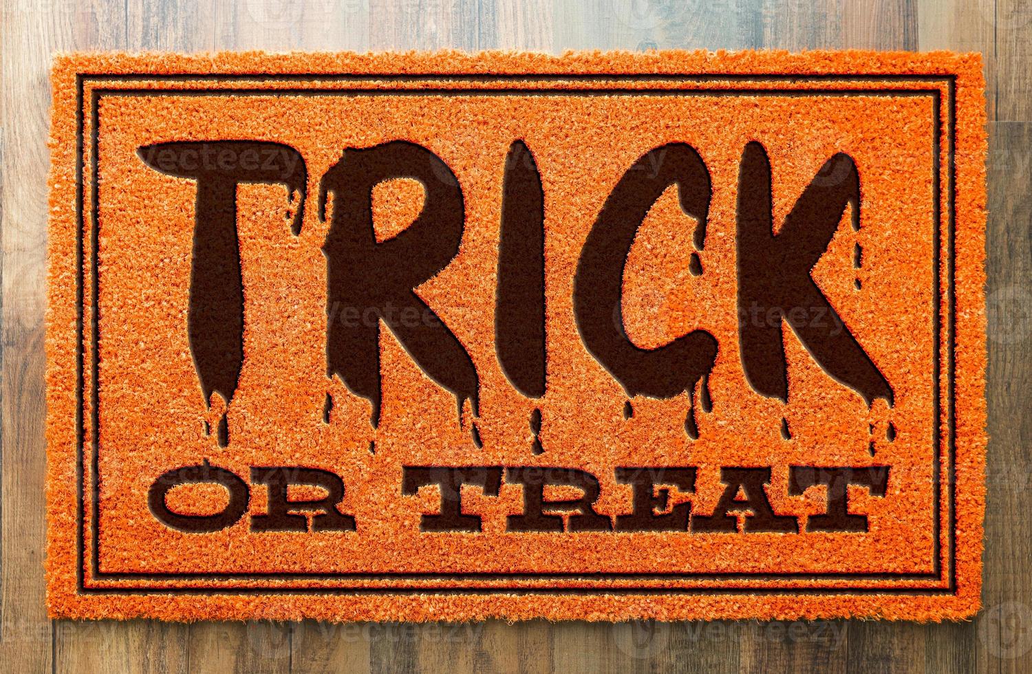 Trick Or Treat Halloween Orange Welcome Mat On Wood Floor Background photo