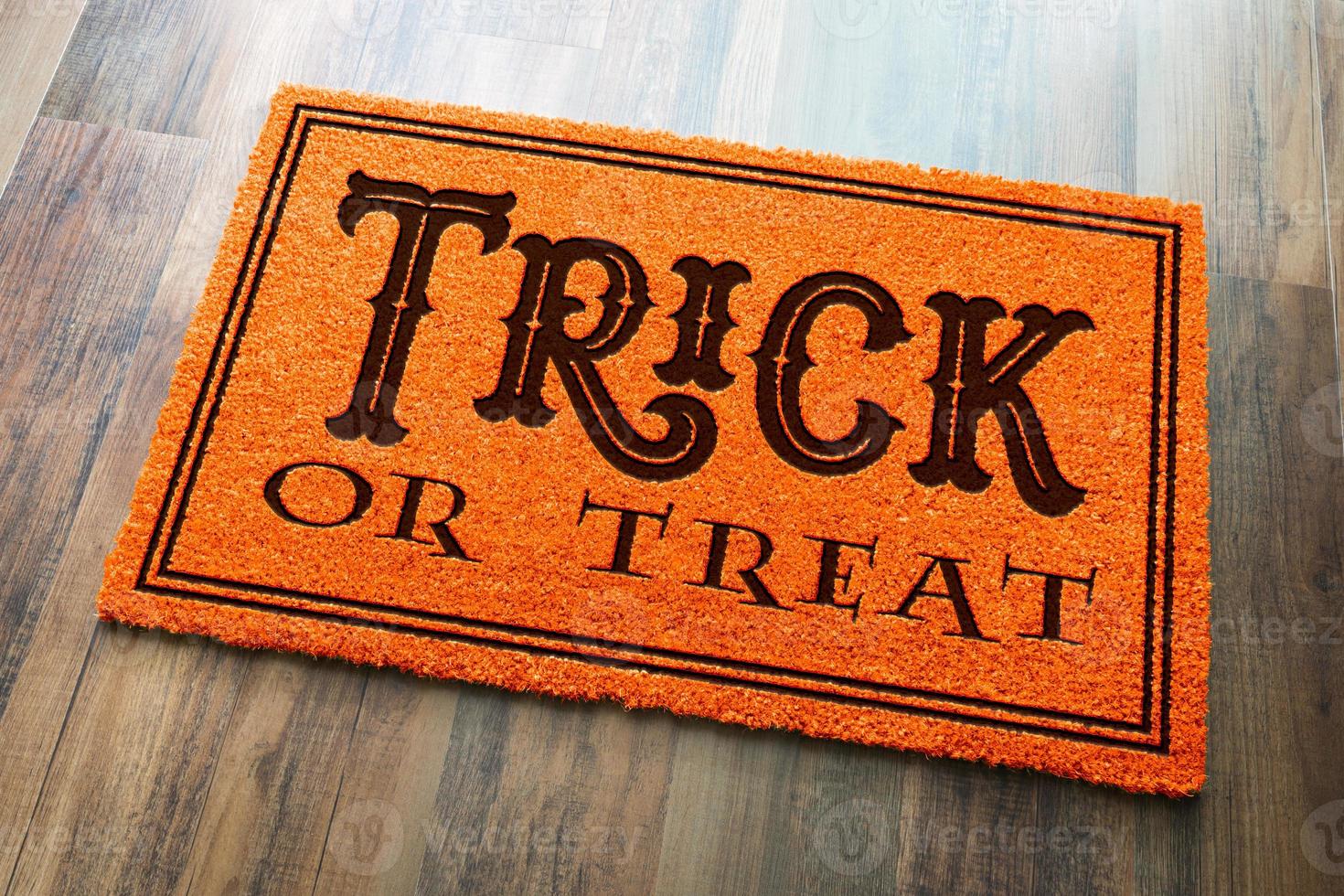 Trick Or Treat Halloween Orange Welcome Mat On Wood Floor Background photo