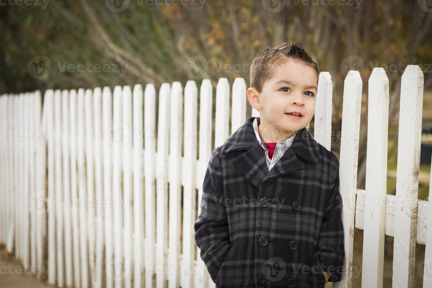 Young Mixed Race Boy Waiting For School Bus Along Fence Outside. photo