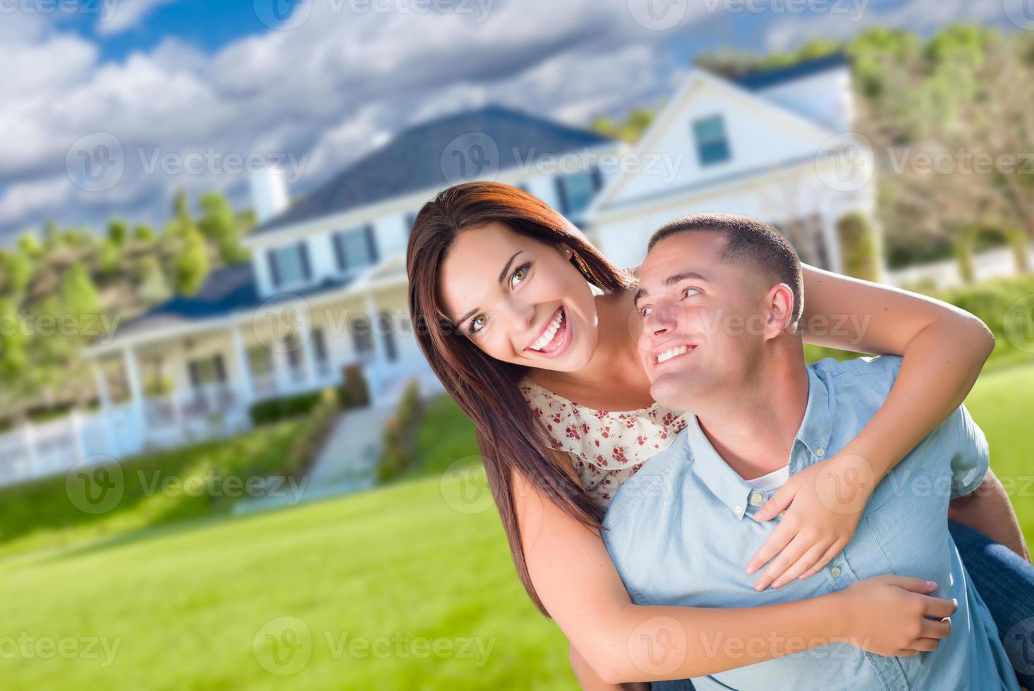 Playful Young Military Couple Outside A Beautiful New Home. photo