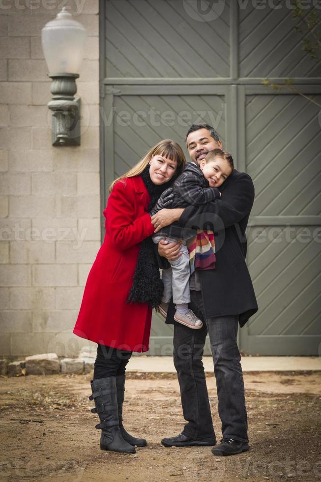 Warmly Dressed Family Loving Son in Front of Rustic Building photo