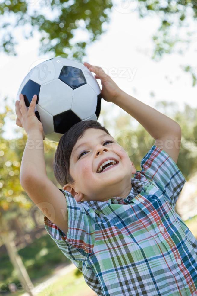 Lindo niño jugando con balón de fútbol al aire libre en el parque. foto