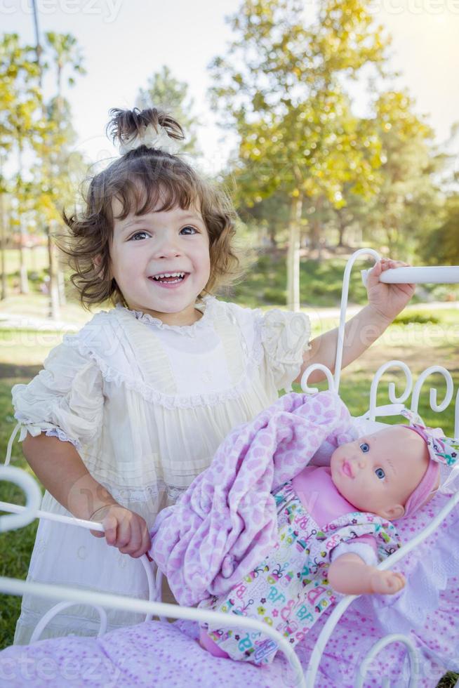 Adorable Young Baby Girl Playing with Baby Doll and Carriage photo