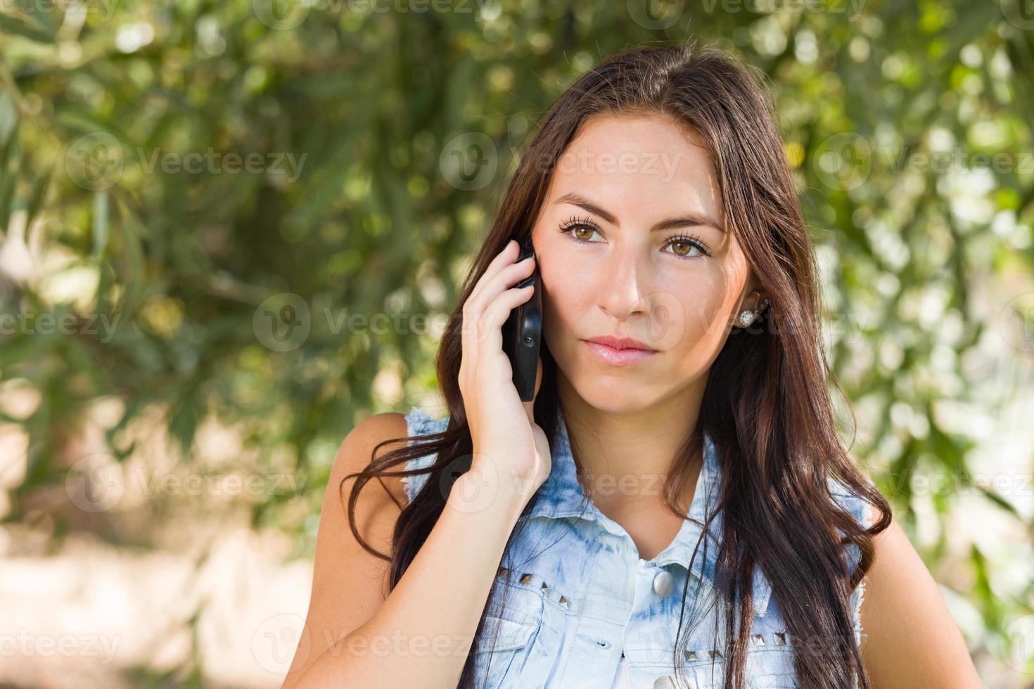 Mujer joven de raza mixta infeliz hablando por teléfono celular afuera foto