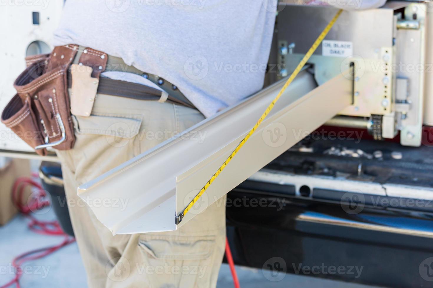 Worker Measuring Rain Gutter Processing Through Seamless Shaping Machine photo