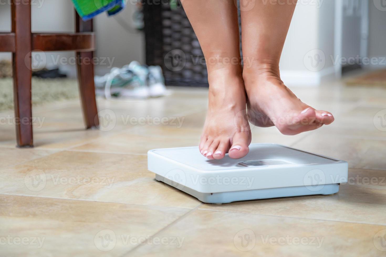 Woman Floating Slightly Above Surface of Weight Scale photo