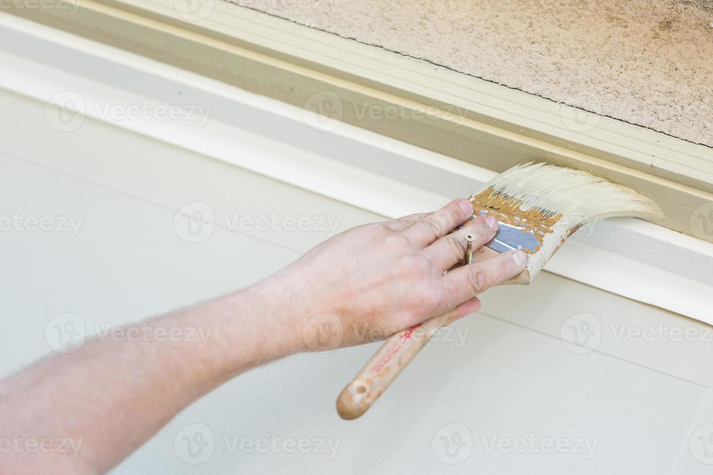 Professional Painter Cutting In With Brush to Paint Garage Door Frame photo