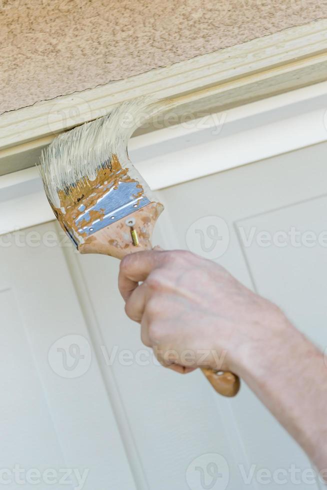 Professional Painter Cutting In With Brush to Paint Garage Door Frame photo